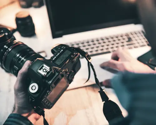 An image of a photographer at a desk with a camera and computer.