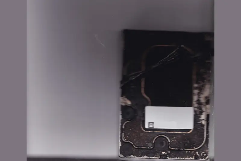 Close-up of a damaged electronic component with wires and a white label.