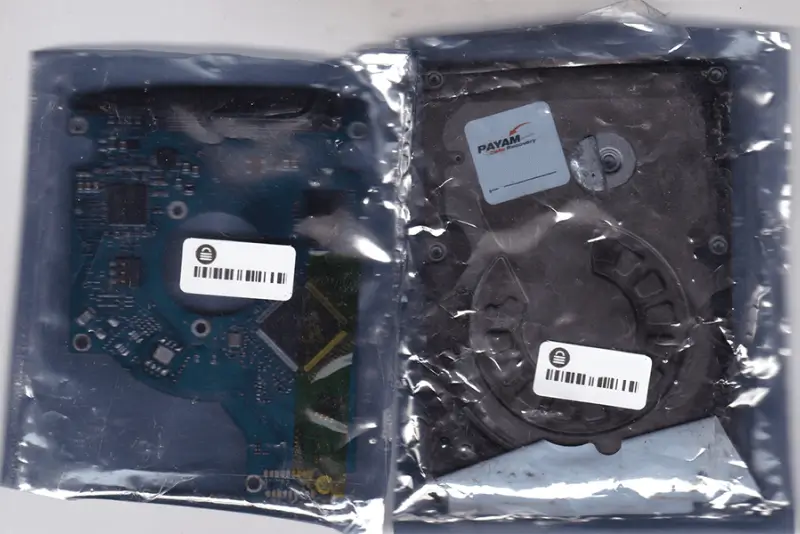 Two hard drive components in plastic packaging. One is a circuit board, the other is the drive itself. | e Ο PAYAM