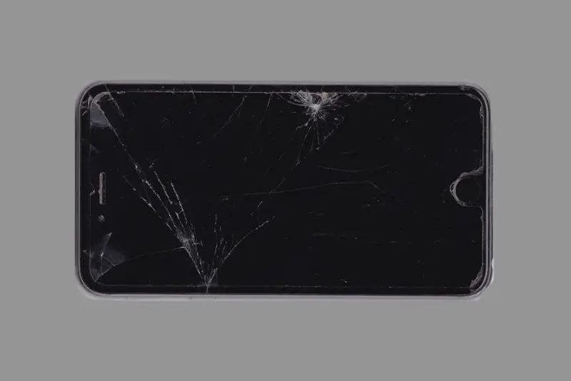 A black smartphone with a heavily cracked screen.