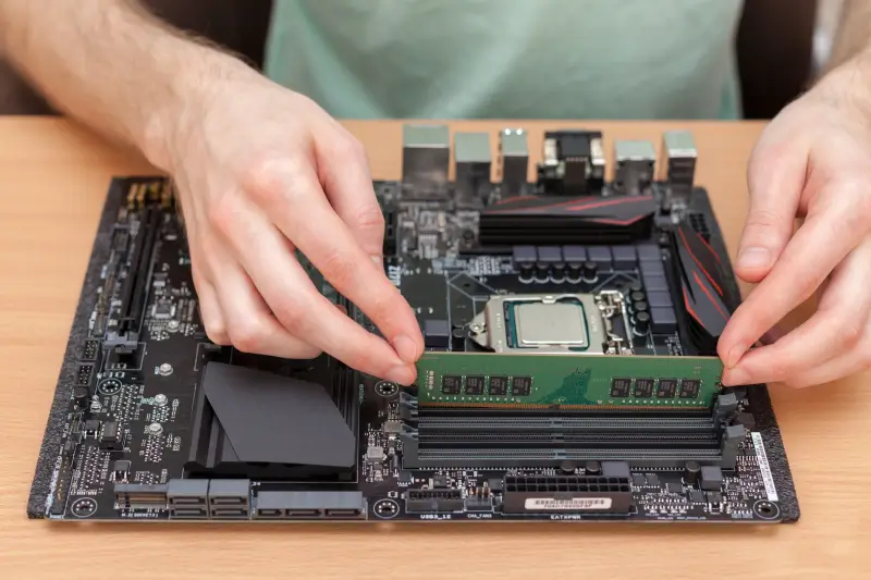 A technician inserting RAM modules into the motherboard of a computer.