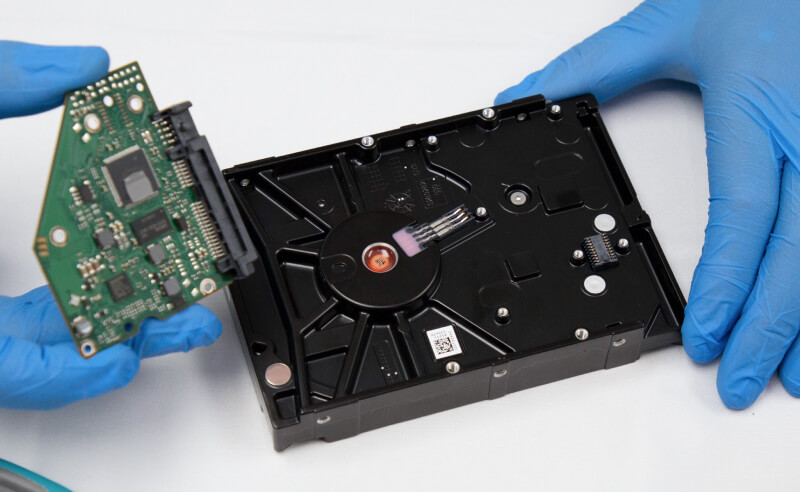 An image of a data recovery engineer holding the printed circuit board of a hard drive.