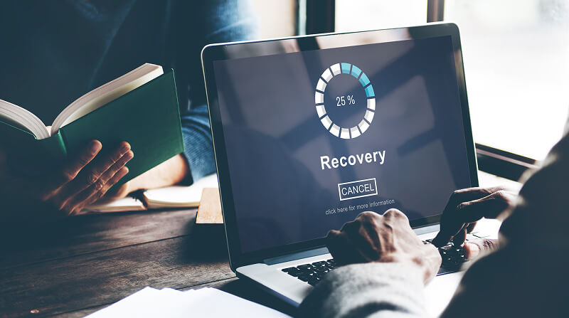 A man with a laptop attempts to recover deleted files.