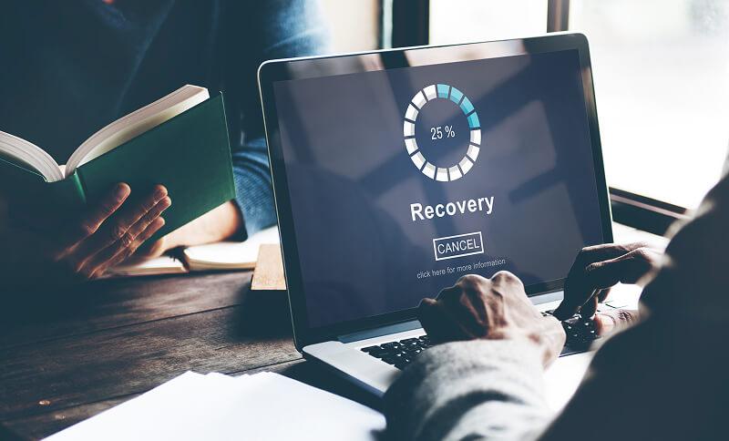 Data recovery software runs on a laptop to restore lost files.