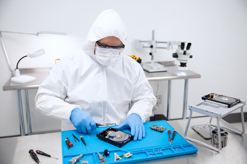 An image of a data recovery engineer disassembling a hard drive in a cleanroom.