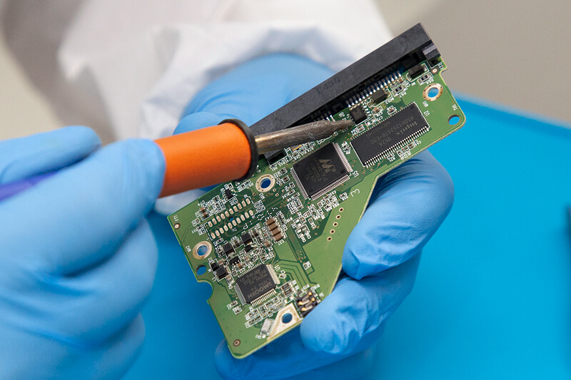 An image of a data recovery engineer holding a hard drive’s PCB.