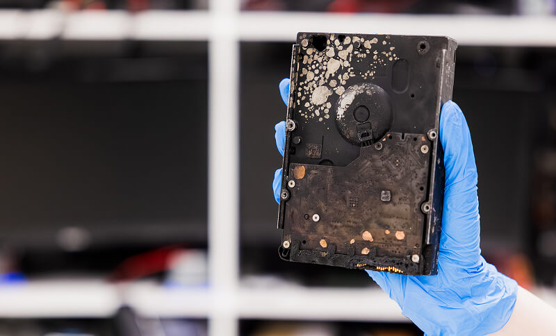A data recovery engineer holding up a physically damaged hard drive.