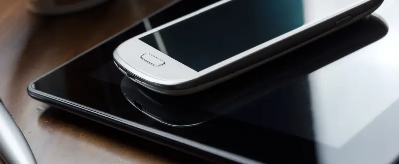 An image of a smartphone and tablet sitting on a table.