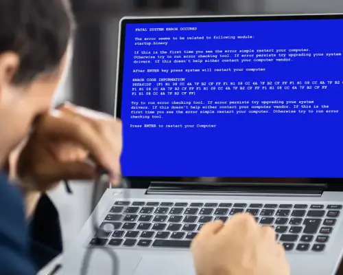 A stressed man reacts to experiencing data loss on his laptop.